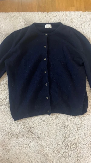 Mörkblå kofta från H&M - Klassisk mörkblå kofta från H&M med rund halsringning och knappar framtill. Koftan har lång ärm och är tillverkad i ett mjukt stickat material som passar perfekt till lager på lager. Enkel och stilren design som funkar till det mesta.