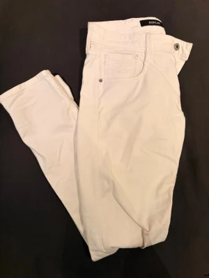 Vita jeans från Replay - Säljer ett par snygga vita jeans från Replay, modell Ambass. Klassisk femficksdesign med raka ben och knappgylf. Perfekta för dig som vill ha en clean och stilren look. Materialet känns mjukt och följsamt.