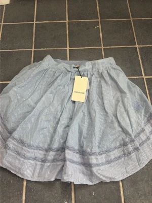Blå glittrig kjol från Zara - Supersöt blå kortkjol från Zara med glittriga detaljer och volang längst ner. Kjolen har ett lätt och luftigt material som ger en skön känsla och passar perfekt till varmare dagar. Elastisk midja för extra komfort.