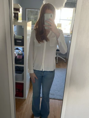 Vit skjorta med fickor fram - Säljer en stilren vit skjorta med två bröstfickor och knappar framtill. Skjortan har lång ärm och är gjord i ett tunt, lätt material som känns luftigt. Det går även att knäppa upp vid armen som man ser på bild 4. Aldrig använt 💕