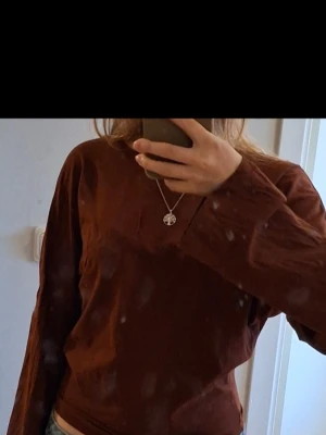  långärmad tröja i bomull - Snygg rostfärgad långärmad tröja med avslappnad passform och rund halsringning. Tillverkad i mjukt bomullstyg, perfekt att matcha med jeans eller kjol. Enkel och stilren design utan tryck eller mönster.