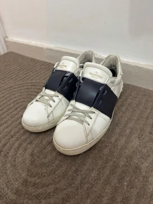Valentino Open sneakers med blå detalj - Säljer ett par exklusiva skor från Valentino. Skorna är i mycket fint skick och väl omhändertagna. Allt original ingår – låda, dust bags samt kvitto, vilket gör detta till ett perfekt köp även för dig som vill ha ett komplett set. Detaljer: Skick: Mycket fint Originalförpackning: Ja (låda & dust bags) Kvitto: Ja Pris: 2499 Observera att jag kan skicka skorna först från och med 1 maj. Säljes då de inte längre används. Hör av dig vid intresse eller frågor!