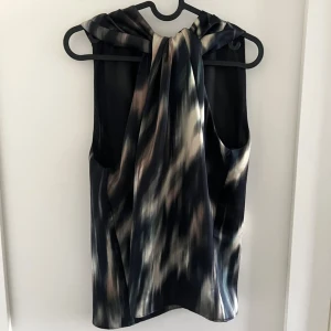 Mönstrad blus med knyt  - Snygg ärmlös blus med abstrakt mönster.