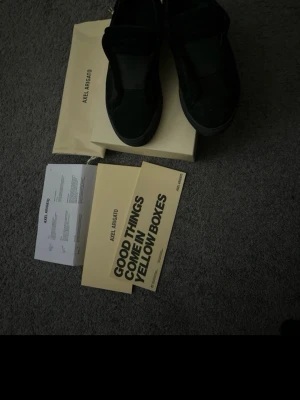 Svarta sneakers från Axel Arigato - Snygga svarta sneakers från Axel Arigato med minimalistisk design. Skorna har en låg siluett och är tillverkade i mocka och läder. Kommer med originalförpackning och dustbag. Perfekta för dig som gillar stilrena och trendiga skor.