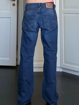 Blå jeans från Diesel  - Säljer ett par blå jeans från Diesel med fem fickor, tydliga sömmar och knappjylf. Avslappnad passform, aldrig använda i min ägo, inga slitningar eller defekter. Midjemått på 39cm rakt över samt innerbenslängd på 78cm. Vid frågor eller önskemål om fler bilder är det bara att skriva privat. 💕