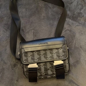 Lacoste Väska - Säljer min Lacoste väska då jag inte har nån användning för den. Väskan är i 10/10 skick, inga fel eller så. Köpt för 2100kr hos Lacoste. Om du har frågor eller är intresserad så är det bara att höra av dig🤝