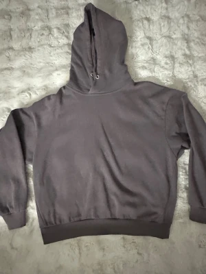 Mörkgrå oversized hoodie - En enkel och stilren mörkgrå hoodie med huva och dragsko. Hoodien har breda muddar vid ärmslut och nederkant, samt en avslappnad, oversized passform. Perfekt för en chill och casual look.