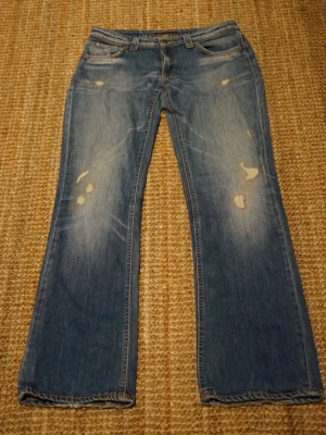 Bootcut Nudie Jeans 2010 - Säljer mina Nudie Jeans, modellen är Slim Jim/bootcut och i storleken 30/32. Lappen har blivit utsuddad men de sitter som Slim Jim/bootcut.   Mått här 👇  Totallängd: 101 cm Midjabredd: 40 cm  Benslut: 22 cm  Skick: 	•	De är i fint skick med riktigt snygga fades och slitningar, det enda är att de har lite heelbite alltså att de är slitna nere vid slutet på jeansen.  - Dessa jeansen är från någonstans runt 2010!   Fråga gärna om du vill ha fler bilder! Pris ej hugget i sten!  Kolla min profil för 