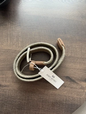 Beige flätat bälte från John Henric - Säljer ett snyggt beige flätat bälte från John Henric.