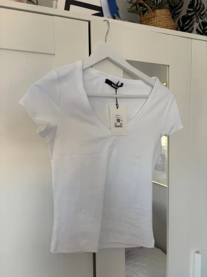 Vit v-ringad t-shirt från Bik Bok - Vit T-shirt från Bik Bok aldrig använd💕 