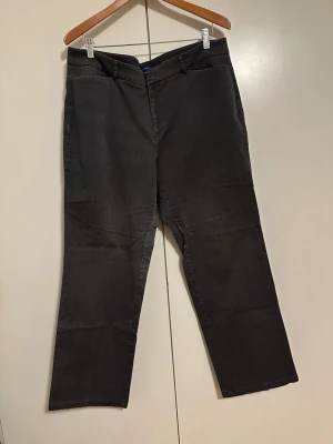 Mörkgrå chinos med raka, breda ben - Snygga mörkgrå chinos med klassisk rak passform och bälteshällor. Byxorna har två fickor fram och två passpoalfickor bak. Tillverkade i ett mjukt bomullsmaterial som ger en skön känsla hela dagen. Perfekta för dig som gillar en clean och enkel stil.