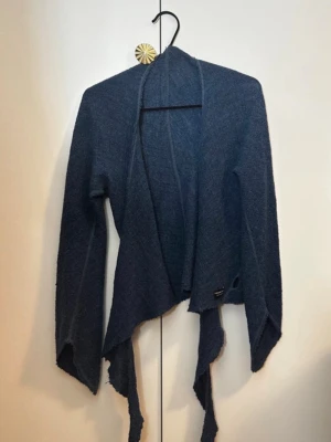 Omlottkofta i Ull - Säljer en mörkblå långärmad omlottkofta med utsvängda ärmar. Funkar som XS,S & M.                 100% Ull.                                                             Hör av dig vid frågor!☺️