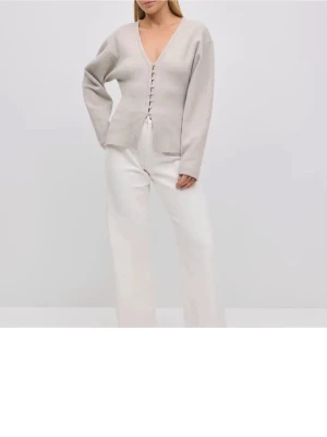 Beige kofta med knappar - Snygg beige kofta med djup V-ringning och knäppning framtill. Koftan har långa ärmar och en rak, avslappnad passform. Perfekt att styla lager på lager och passar till det mesta i garderoben.