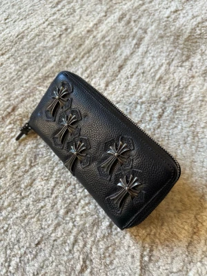 Chrome Hearts Quintuple Cross Large Leather Wallet  - Säljer en svart chrome hearts plånbok i läder med silver korsdetaljer på framsidan. Plånboken har dragkedja runtom, 9 kort fack och 5 Stora fack. Längd: 20cm  Höjd: 10cm  Bredd: 4cm