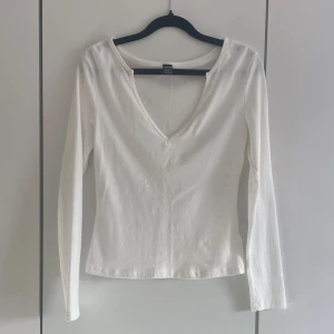 Vit långärmad v-ringad tröja - Klassisk vit långärmad topp från SHEIN med v-ringning. Tillverkad i mjuk bomull med en slim passform som sitter snyggt på kroppen. Perfekt basplagg att styla till olika outfits. Knappt använd 