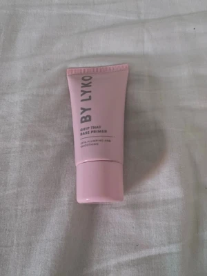 By Lyko Grip That Base Primer - Grip That Base Primer från By Lyko i en ljusrosa tub med skruvlock. Primern är framtagen för att ge en jämn och slät bas, och har texten 'skin-plumping and smoothing' på förpackningen. Perfekt för att förbereda huden innan makeup.