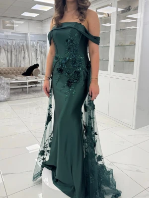 Mörkgrön offshoulder balklänning - Balklänning/högtidsklänning använd en gång. Köpt på Remanns högtidskläder. Nypris 4500 kr. Jättefint släp med glittriga detaljer. Storleken är skräddarsydd för mig som vanligtvis har S/36-38 och vid bysten passar mig med ungefär 70B, men skulle gå med större också. Längden är lagom/lång för mig som är 172