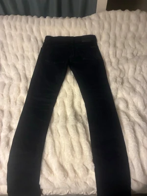 Nudie jeans - Säljer ett par svarta med klassisk femficksdesign och smal passform. Jeansen har normal midja och raka ben. Perfekta till en avslappnad streetstyle-look. Materialet är stretchigt för extra komfort.