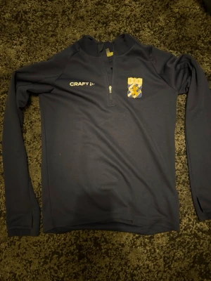 Mörkblå långärmad IFK Craft tröja - Säljer en mörkblå långärmad IFK GÖTEBORG träningströja Tröjan har halv dragkedja framtill och är tillverkad i ett mjukt, funktionsmaterial som passar perfekt till träning, uppvärmning eller bara chill outfit!