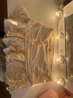 Beige volangkjol från Nelly - Supersöt beige kortkjol från Nelly med volangdetaljer. Kjolen är tillverkad i ett lätt linnematerial och har en avslappnad passform som ger en skön och trendig look. Perfekt att styla med en enkel topp eller stickad tröja.
