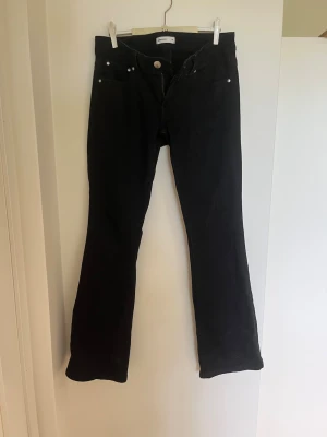 Svarta bootcut jeans med silverknappar - Snygga svarta jeans med bootcut passform och silverfärgade knappar. Jeansen har låg midja. Jeansen har en stilren look och passar perfekt till en trendig vardagsoutfit. 