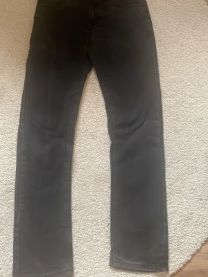 Svarta raka jeans från Levi's - Säljer ett par klassiska svarta jeans från Levi's med rak passform. Jeansen har fem fickor, diskret röd Levi's-lapp på bakfickan och är tillverkade i ett mjukt bomullsmaterial. Perfekta för en clean och stilren look.