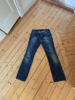 Blå jeans från Replay bootcut - Säljer ett par klassiska blå jeans från Replay med bootcut-modell. Jeansen har slitningar och ljusare partier på låren för en cool, använd look. Perfekta till vardagsstilen!