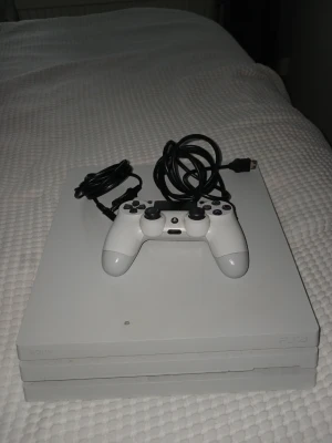Vit PlayStation 4 Pro med handkontroll - Säljer en vit PlayStation 4 Pro med matchande vit DualShock 4-handkontroll och tillhörande kablar. Konsolen har en stilren, fyrkantig design med PlayStation-loggan på ovansidan. Perfekt för gaming och streaming.  Med ps4an kommer det en hdmi kabel, ström kabel och en ps4 kontroll
