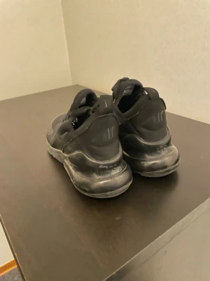 Nike Air Max 270 helsvarta sneakers - Säljer ett par helsvarta Nike Air Max 270 sneakers med mesh-ovandel och synlig Air-enhet i sulan. Skorna har en sportig look med diskret Nike-logga på sidan och dragflik bak. Perfekta för dig som gillar stilrena och bekväma sneakers.