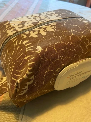 Liten skötväska / fodral för våtservetter /blöjor, handsytt - Liten skötväska / fodral för våtservetter /blöjor, handsytt  Beskrivning: Handsytt fodral för blöjor samt med smart hål för att trä dit våtservetter med lock. Utöver våtservetter rymmer du ca 12-15 blöjor storlek 5 och ombyte.  Passar de flesta standardförpackningar med upp till ca 72 våtservetter. Perfekt att ha i skötväskan, bilen, vagnen eller hemma.  ✨ Handgjord ✨ Återanvänt plastlock från originalförpackning ✨ Dragkedja för enkel påfyllning ✨ Praktiskt bärhandtag ✨ Tvättbart tyg   Mått: ca 