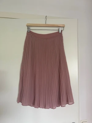 Pieces rosa plisserad kjol, XS - Säljer min rosa plisserade kjol från Pieces! Använd en del men fortfarande som ny.   Kjolen är 66cm från övre till nedre kant, slutar typ under knäna. Dragkedja i sidan.