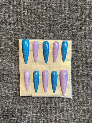 Press-on naglar || Storlek M - Säljer ett set stilettoformade press-on naglar i glittrigt blått och lila. Naglarna har en snygg, lång och spetsig design med skimrande finish som verkligen sticker ut. Perfekt för dig som vill ha en färgstark och trendig look. Glittret är holographic! Storlek M, Det du får med dig : * Fil och manikyr pinne * nagellim klistermärken * 2 lappar av rengöring för naglar.