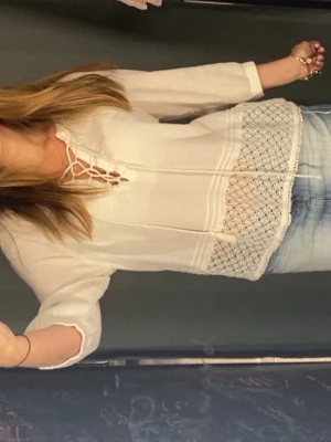 Vit boho-blus från victorias secret  - Säljer en vit/ crémefärgad blus i boho-stil med fina spetsdetaljer och knytning vid halsen. Blusen har trekvartsärm och ett luftigt, lätt material som ger en avslappnad känsla. Har inga defekter förutom att en av tofsarna fattas på ena snöret, syns på första bilden! Storlek M men jag som bär S tycker den e skitskön och passar bra!  Perfekt till jeans eller kjol för en trendig look .