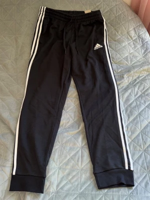 Adidas mjukisbyxor - Helt oanvända adidas mjukisbyxor med prislapp kvar(en del av prislappen har dock klippts och den bruna prislappen på sista bilden har lossnat lite). Byxorna är i storlek L.