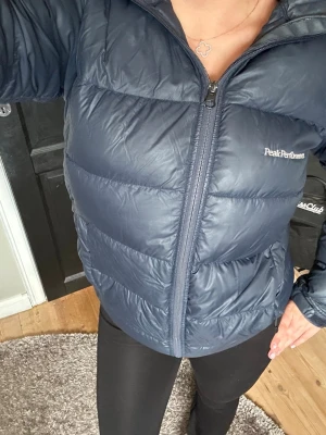 Mörkblå dunjacka Peak Performance - Super snygg mörkblå dunjacka från Peak Performance(170 motsvarar xs i storlek) Den är  använd men i fint skick. Super fin och varm. för fler frågor eller bilder🥰