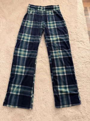 Rutiga pyjamasbyxor från Hunkemöller - Mysiga pyjamasbyxor från Hunkemöller i blått och grönt rutigt mönster. Byxorna har rak passform och resår i midjan för extra komfort. 
