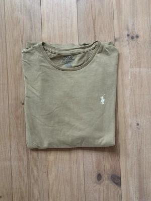 Beige t-shirt från Polo Ralph Lauren - Säljer en beige Ralph lauren t-shirt storlek M. Inga konstigheter, du får varmt höra av dig vid frågor!