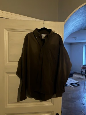 Mörkbrun skjorta från HOPE - Säljer en oversized mörkbrun skjorta från HOPE med klassisk krage och knappstängning framtill. Skjortan har en bröstficka och långa ärmar, perfekt för en avslappnad och stilren look. Materialet känns mjukt och skönt mot huden. 
