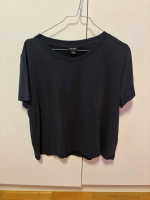 Svart soft  t-shirt från Monki stl L - En enkel svart t-shirt från Monki med rund halsringning och korta ärmar. Tillverkad i en mjuk blandning av modal och polyester som ger en skön känsla och snyggt fall. Perfekt basplagg till garderoben.