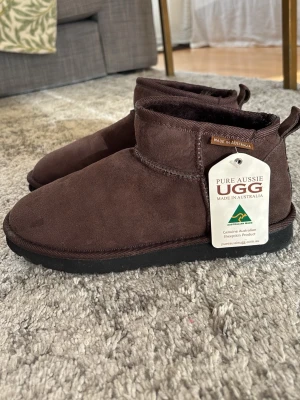Ugg-chokladbrun - Pure Aussie ugg, made in australia. 100% fårskinn Vattenresistenta och fläck-resistenta. Nya med prislapp pga för stora Stl 40 passar precis som en 39. Superfin chokladbrun färg.