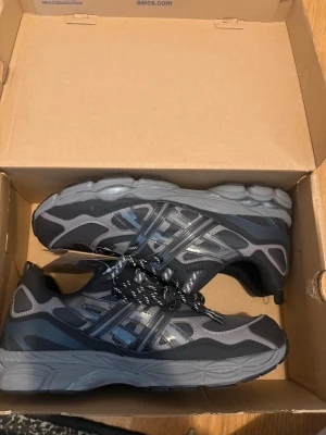 Svarta och grå Asics sneakers - Snygga Asics sneakers i svart och grått. Fick dem i present men tyvärr blev de för små. 