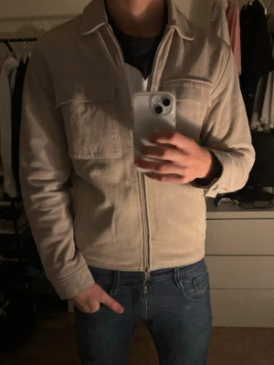 Beige mockajacka  - Stilren beige mockajacka med dragkedja framtill och två stora bröstfickor. Från Human Scales