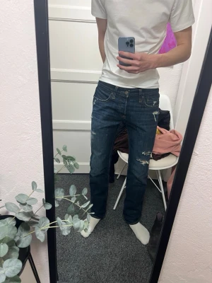 Feta hollister jeans😍 - Säljer ett par mörkblå jeans med raka ben och slitna detaljer på låret och knät. Klassisk femficksmodell med normal midja och dragkedja. Perfekta för dig som gillar en avslappnad och trendig stil.