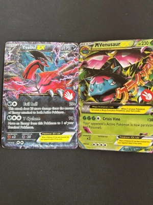 Pokémonkort Yveltal EX & M Venusaur EX - Två Pokémonkort: Yveltal EX och M Venusaur EX. Färgglada motiv med blixtrar och växttema, båda med holografisk yta. Baksidan har Pokémon GO-design med flera populära figurer. Perfekt för samlare eller Pokémonfans.