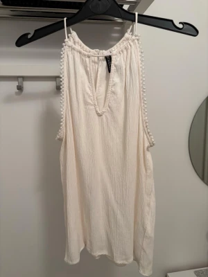 Beige ärmlös topp ny från Hm St.S - Säljer en luftig beige topp från H&M liten öppning fram vid halsen. Toppen har en avslappnad passform och är perfekt för varma dagar. Materialet känns mjukt och lätt mot huden.