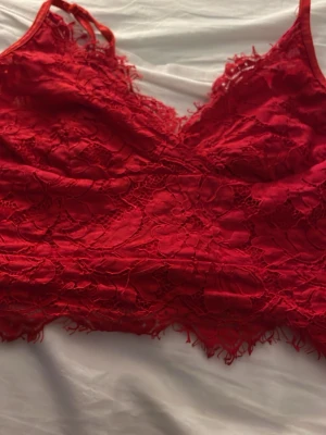 Röd spetsbralette med smala band - Snygg röd bralette i spets med tunna axelband och vacker blommig spetsdetalj. Modellen har en mjuk, stretchig passform och dekorativ kant nertill. Perfekt för dig som gillar feminina underkläder med lite extra detaljer.