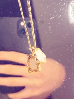 Guldigt halsband med två hängen - Snyggt halsband i guldfärg med två unika hängen. Det ena hänget är en abstrakt rektangulär form och det andra är ett vitt molnformat hänge med guldkant. Perfekt accessoar för att lyfta outfiten. Gå in på mitt konto jag säljer FLERA smycken i olika former och färger. 😊