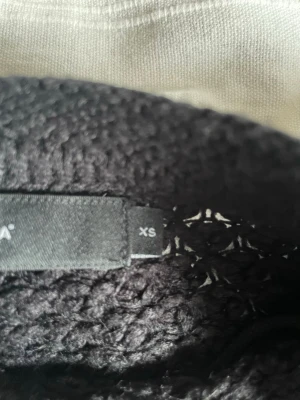 Svart stickad tröja Vero Moda XS - Snygg svart stickad tröja från Vero Moda i storlek XS. Tröjan har en klassisk rund halsringning och grovstickad struktur som ger en trendig look. Perfekt att matcha med jeans eller kjol för en cool vardagsstil.