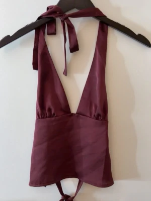 Gina tricot topp - Satin topp i vinröd från Gina tricot som man knyter i nacken och ryggen med band. Super elegant. Oanvänd med lapp kvar