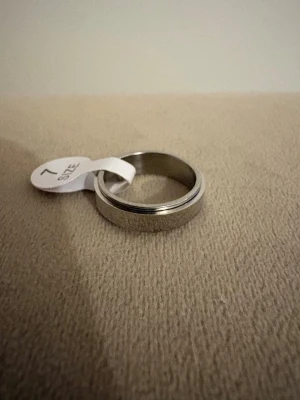 Fidget Ring Spinner – Silverfärgad Anti-Stressring 17,3mm diameter  - Fidget Ring Spinner – Silverfärgad Anti-Stressring   Elegant och rogivande fidget ring i kvalitets metall med silverfinish. Perfekt för dig som vill minska stress, oro eller rastlöshet – snurrdelen rör sig smidigt och tyst.    -Storlek: Innerdiameter 17,3 mm, omkrets 54,4 mm, US7  -Passar: Passar både kvinnor och män och bekväm att bära  -Design: Silverfärgad, Rostfritt stål, Allergivänlig,  Lätt, Unisex, Slitstark – både snygg och funktionell! -Skick: Helt ny med tags   💫Se övriga annonser 💫